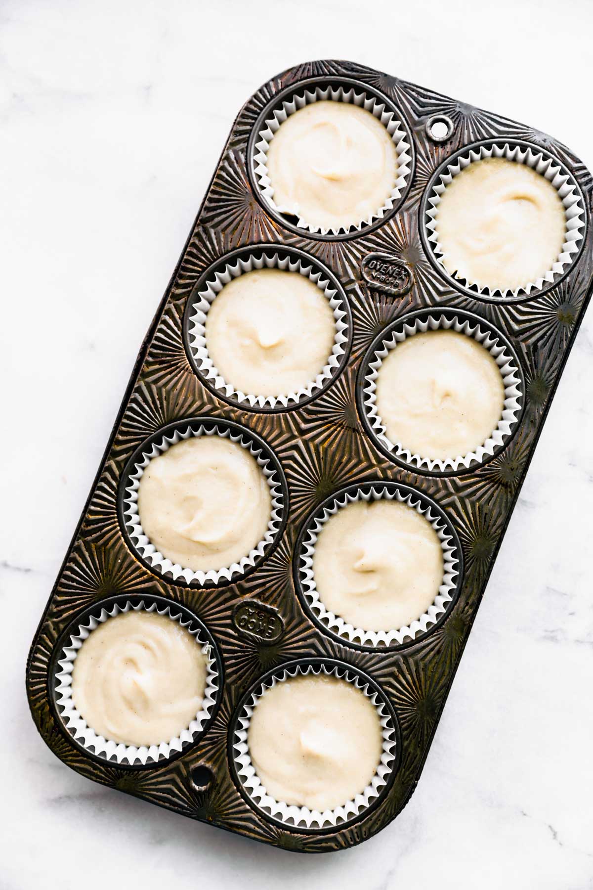 overhead view unbaked vegan vanilla cupcake batter in a 6-count muffin pan