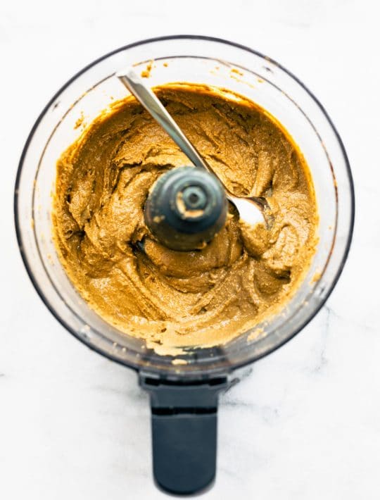 overhead: spoon in the bowl of a food processor, scooping creamy seed butter out