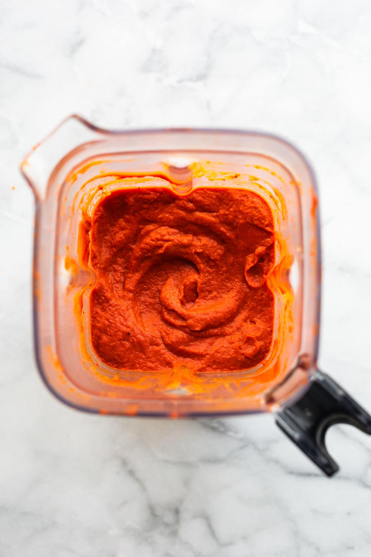 Overhead photo of a red nomato sauce in a blender.