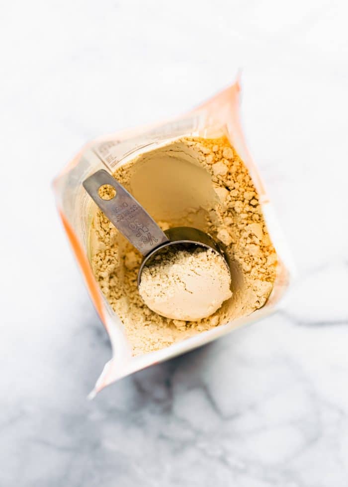 overhead shot: metal measuring cup inside a bag of protein powder