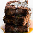 stack of 3 vegan brownies covered with salted caramel sauce