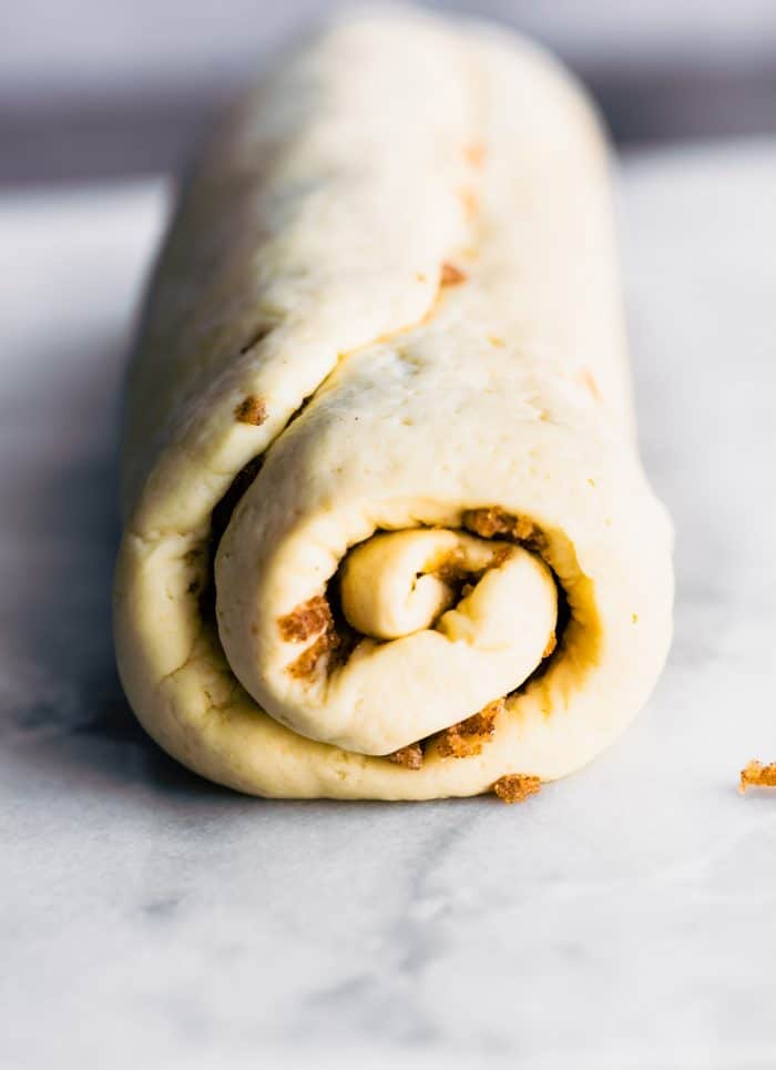 cinnamon roll dough rolled into a log shape, ready for slicing