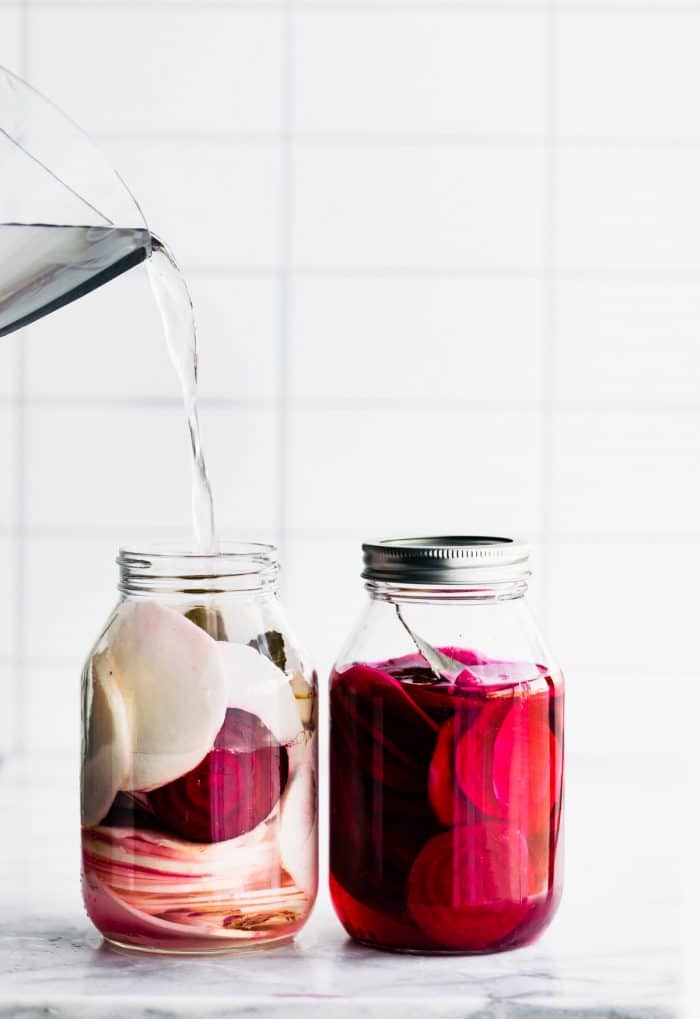 adding vinegar solution (starter liquid) to jar of turnips and beets