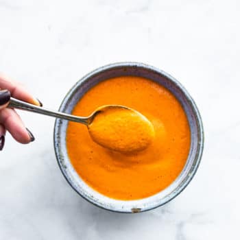 overhead: spoonful of roasted red pepper sauce over bowl of sauce
