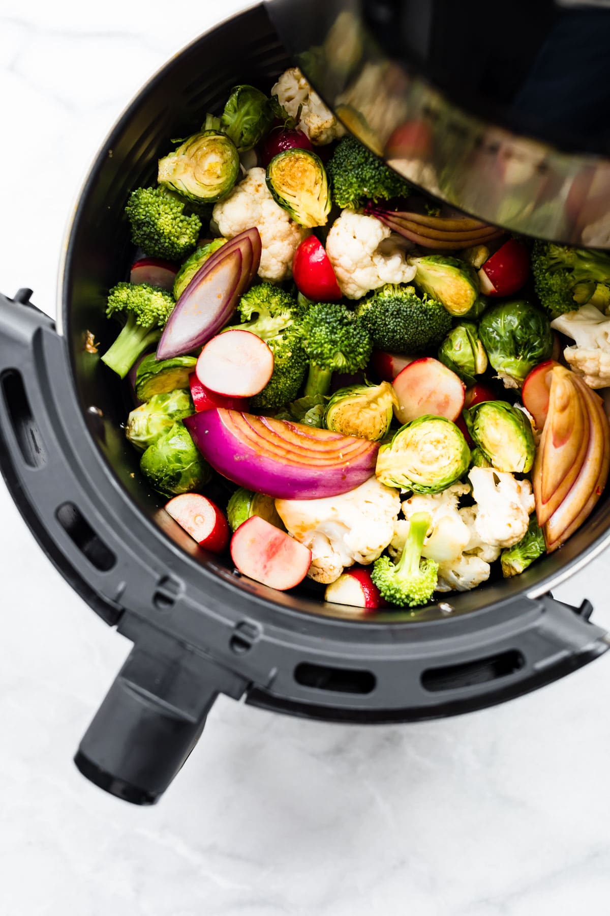 raw fresh veggies in basket of air fryer, ready for cooking