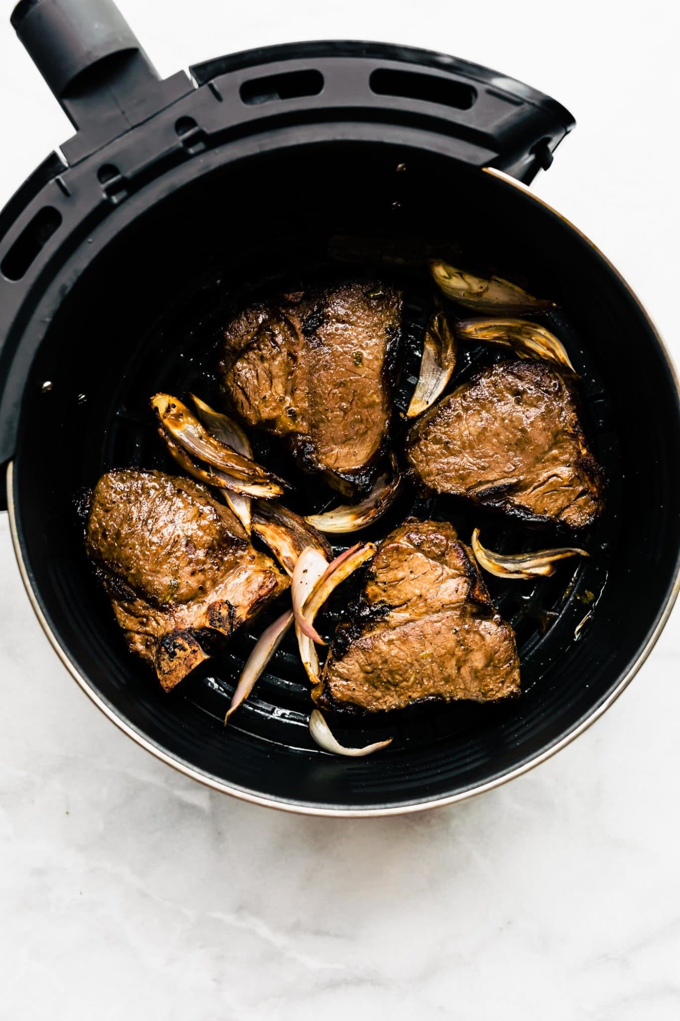 cooked lamb inside an air fryer on a white countertop