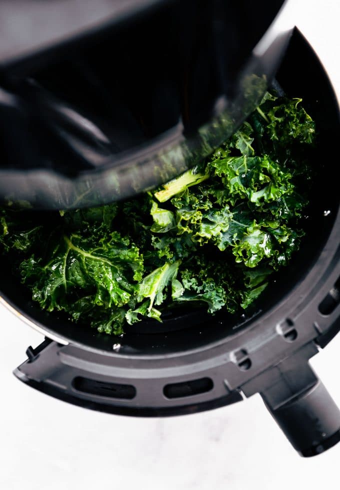 Seasoned kale chips inside air fryer before baking
