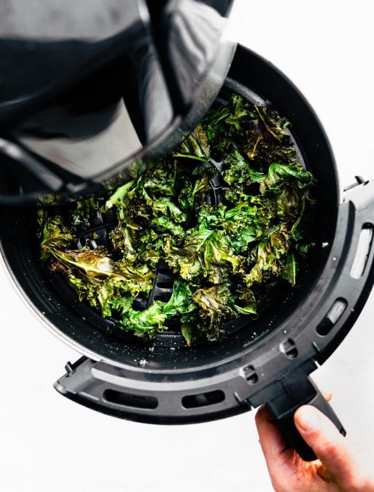 Baked salt and vinegar kale chips being pulled out of the air fryer
