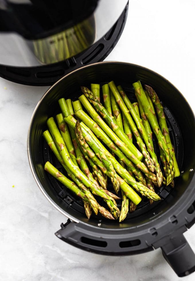 Uncooked asparagus in an air fryer.