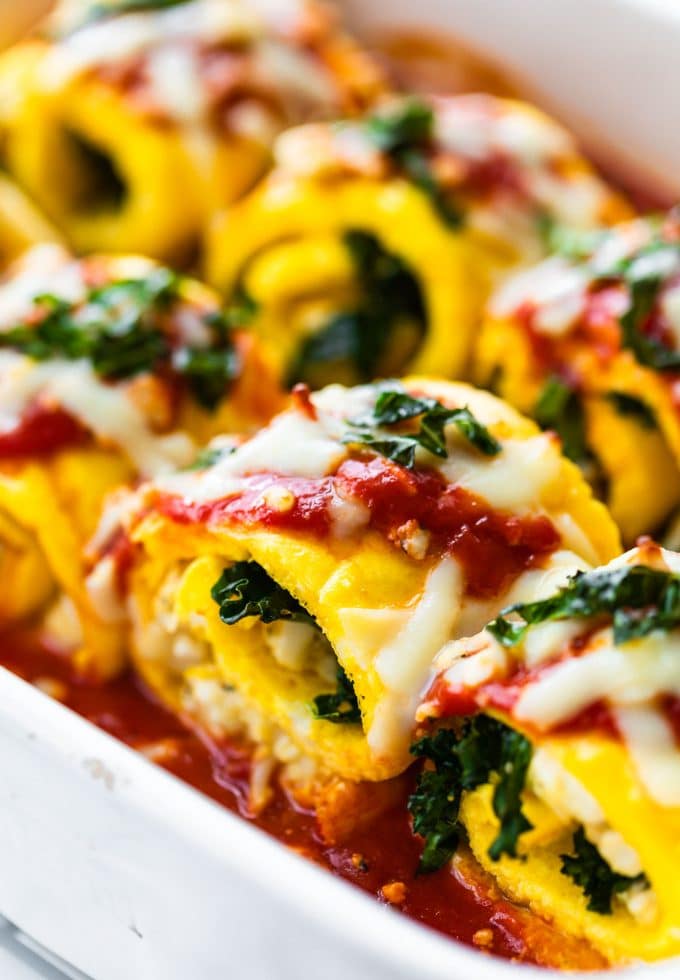 Detail image taken of egg lasagna roll up covered in cheese, sauce, herbs, and baked in the oven.