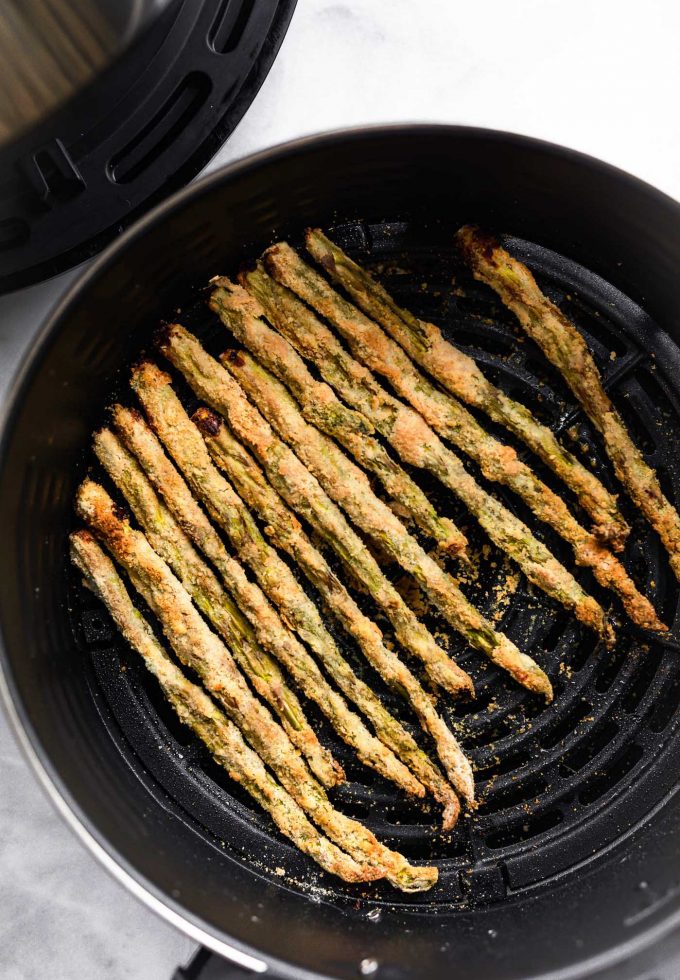 Air fryer asparagus fries lined up in air fryer basket.