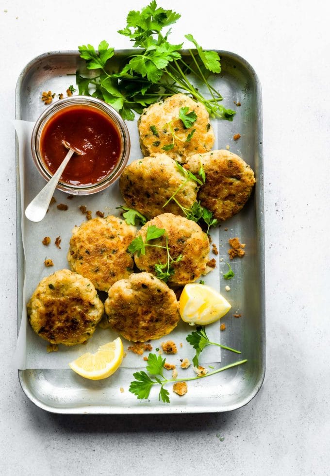Overhead view garlic herb cod cakes on silver baking sheet