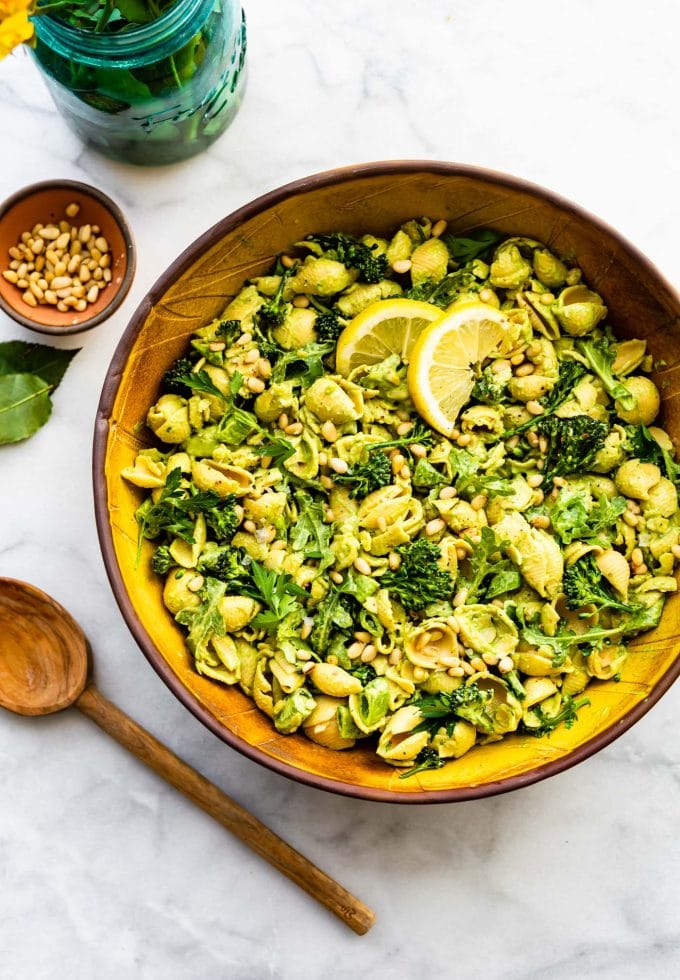 Overhead image of vegan green goddess pasta salad with spoon and flowers.