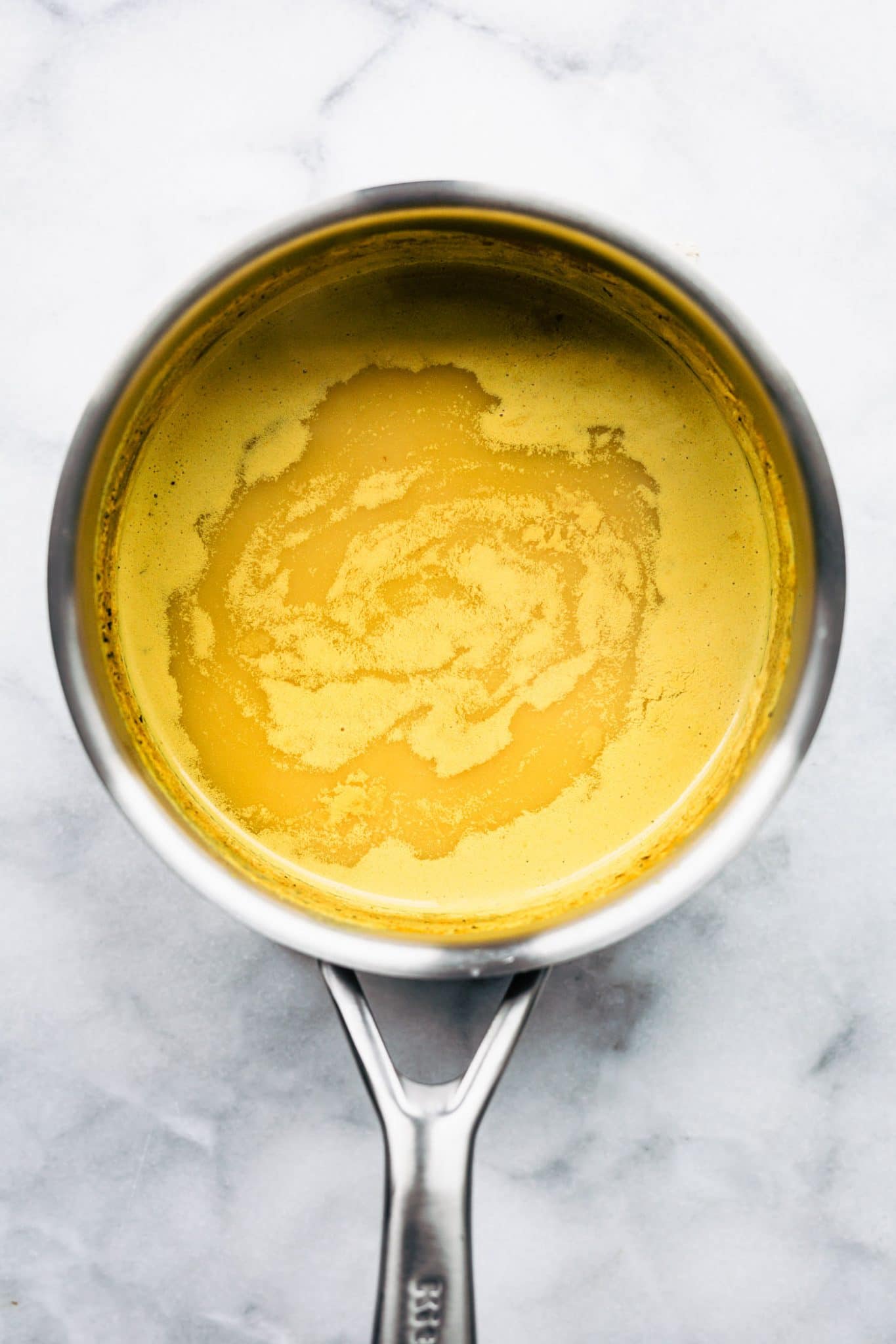 An overhead image of turmeric golden milk in a sauce pan.