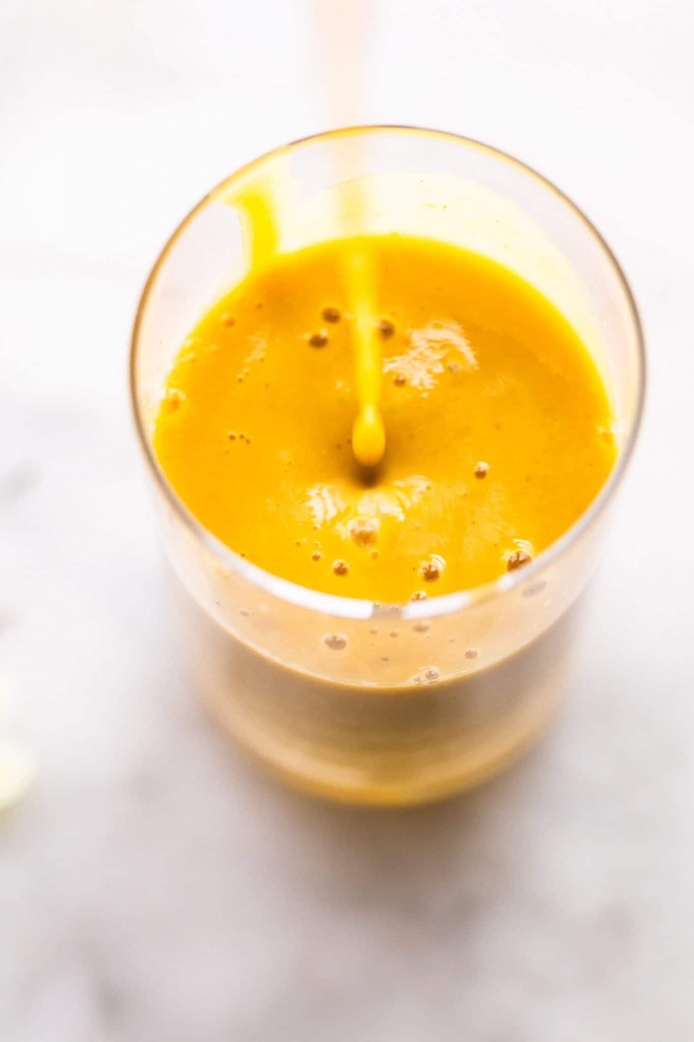 Overhead image of turmeric smoothie being poured into a glass.
