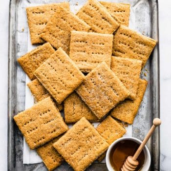 Overhead image of gluten free graham crackers on a sheet pan with honey.