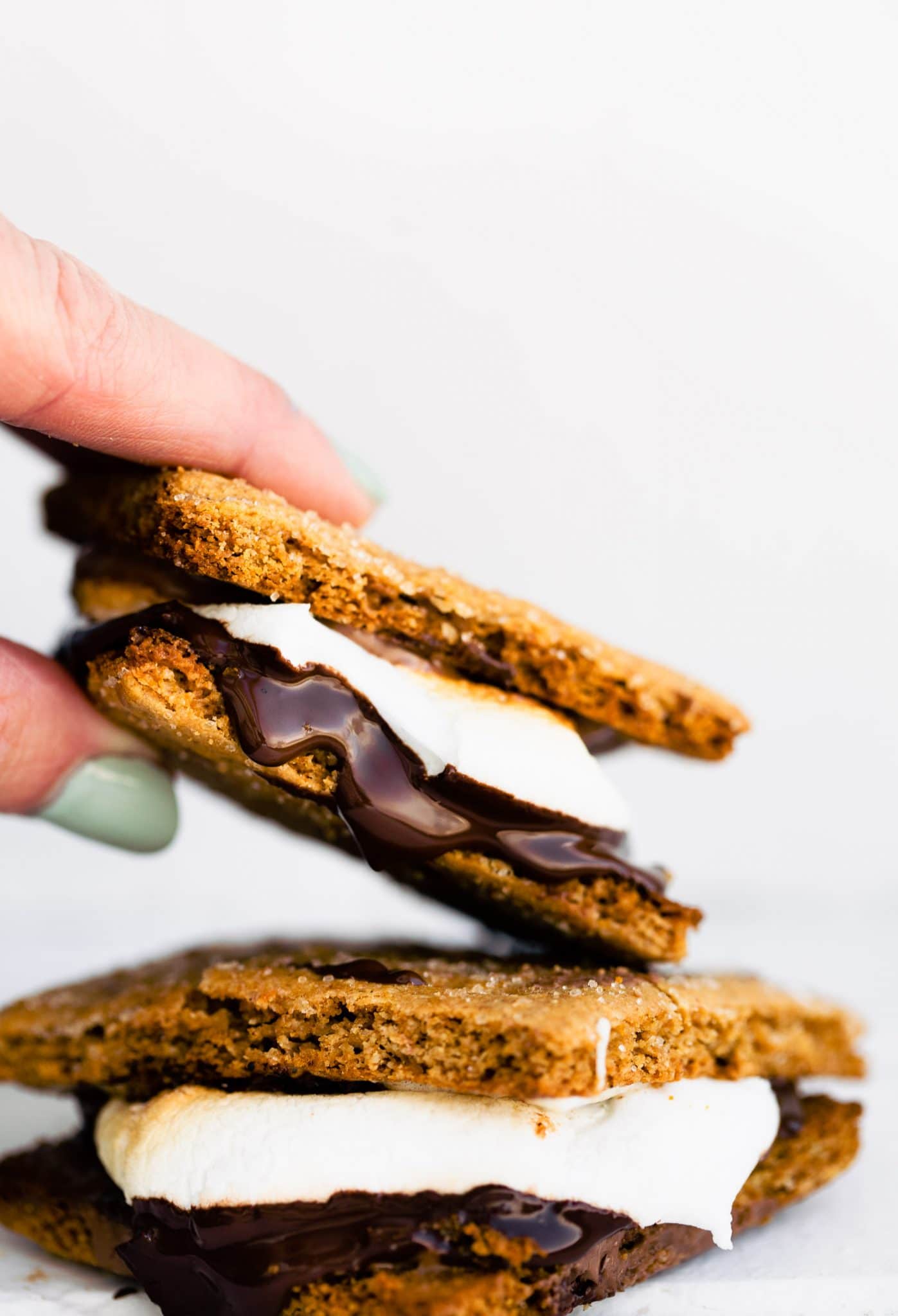 Close up image of a hand grabbing a homemade oven baked gluten free smore from a stack of two.