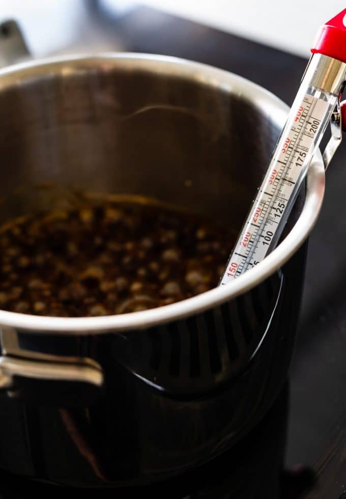 A candy thermometer in a saucepan of boiling ingredients for homemade coconut marshmallows
