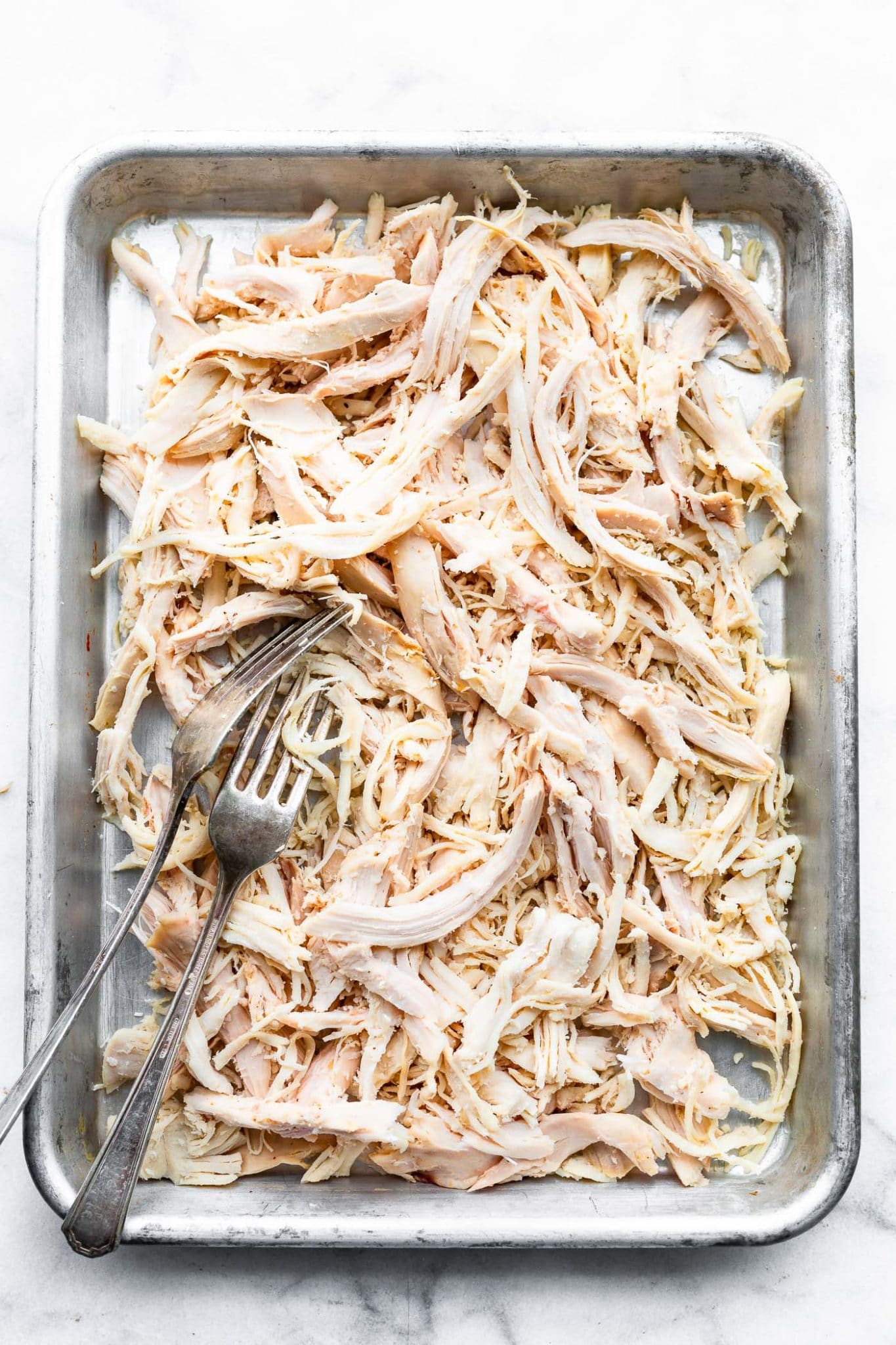 Overhead image of shredded chicken breast on a sheet pan.