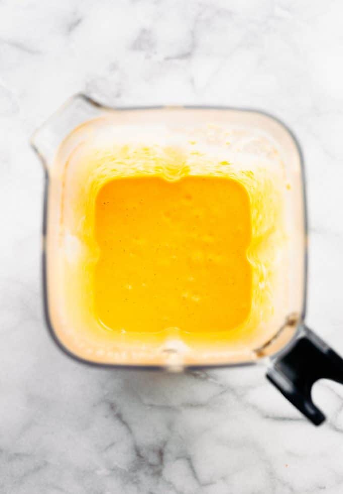 Ingredients for homemade frozen dog treats mixed in a blender to form an orange-yellow batter