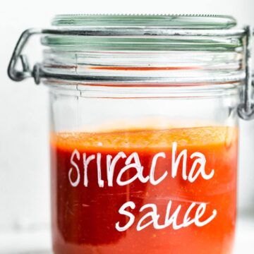 Side view of sriracha sauce in a glass mason jar.