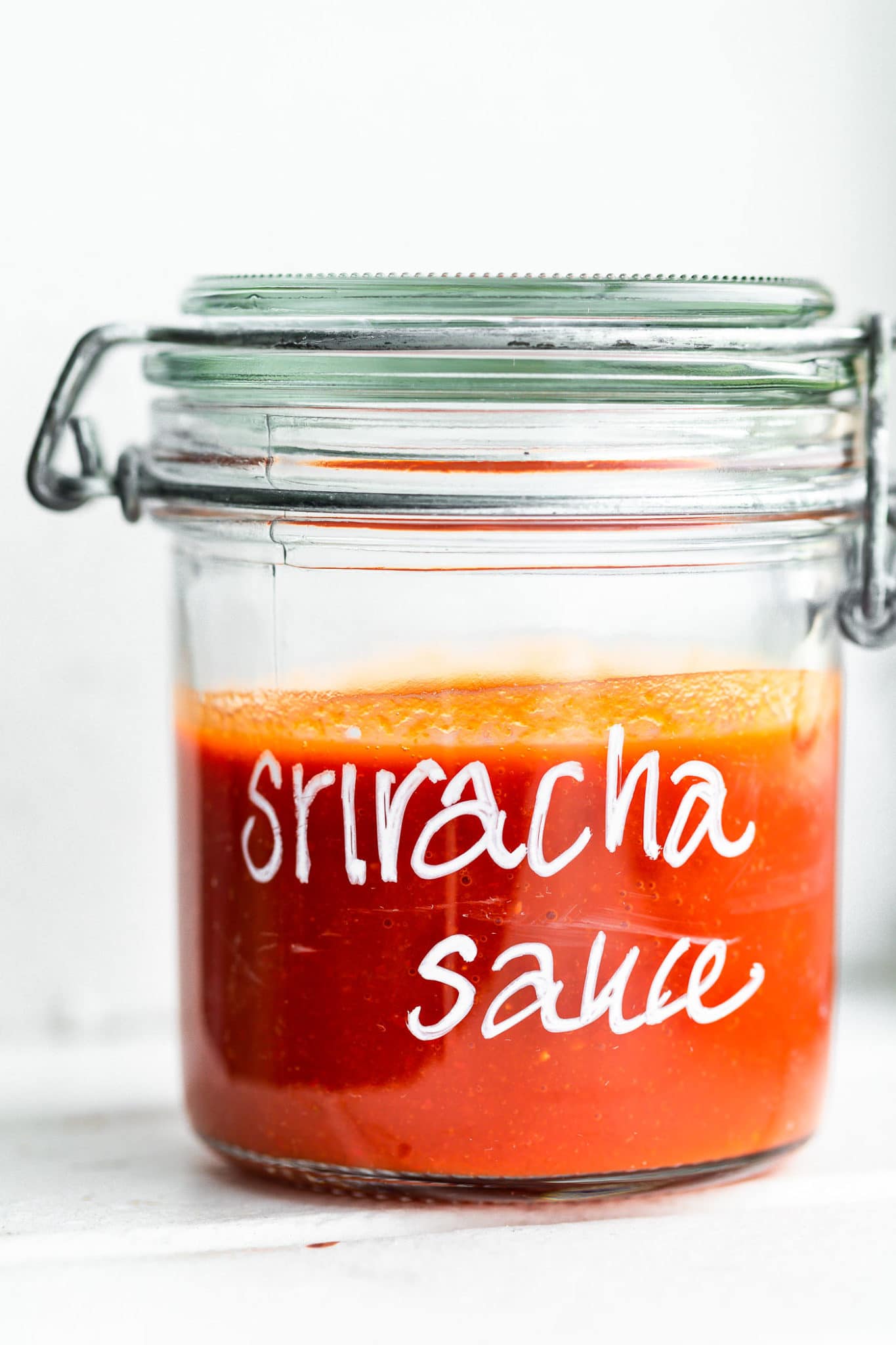 Side view of sriracha sauce in a glass mason jar.