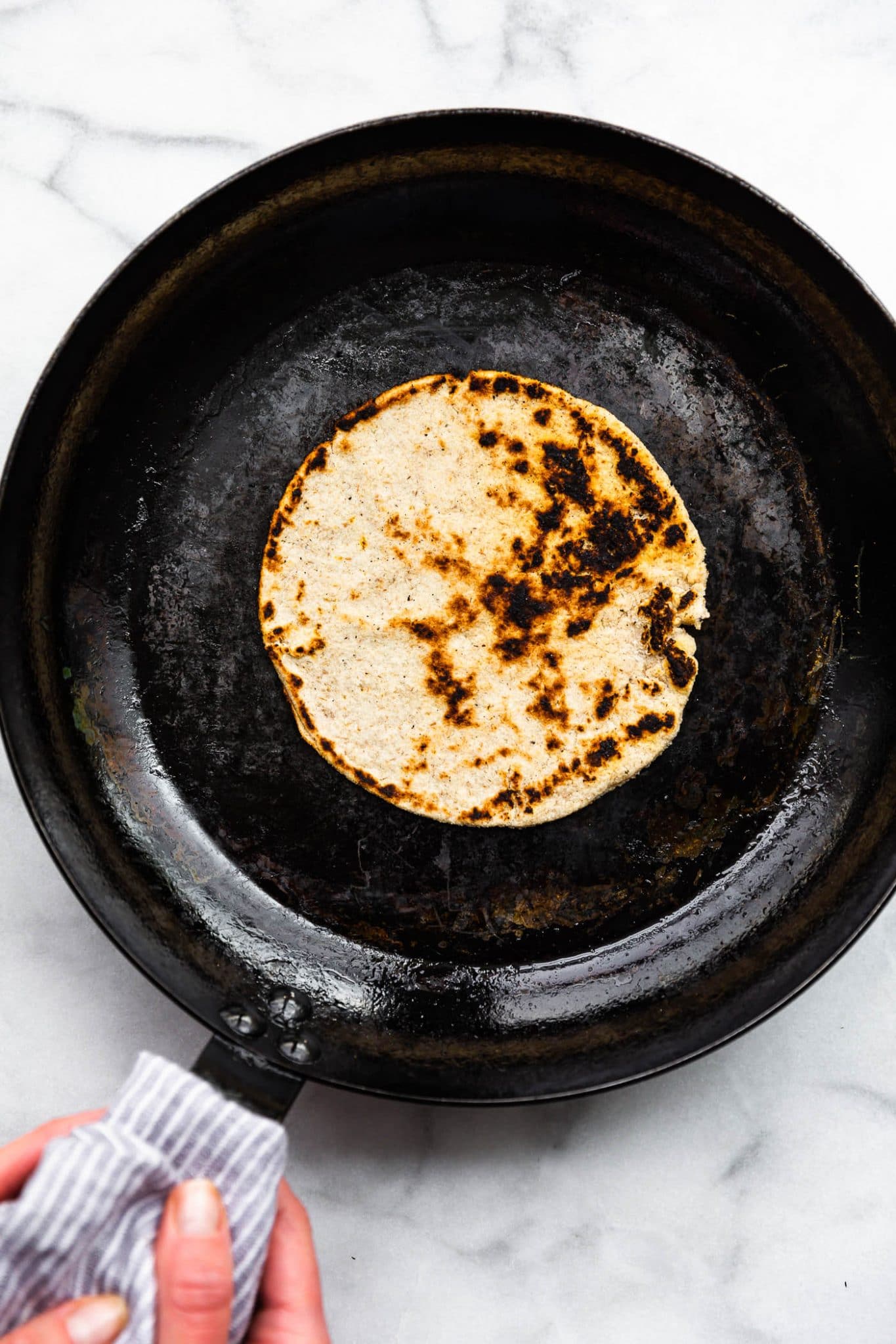 Overhead image of homemade tortillas in a cast iron skillet.