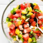 overhead image of watermelon pineapple salsa in a bowl with a spoon