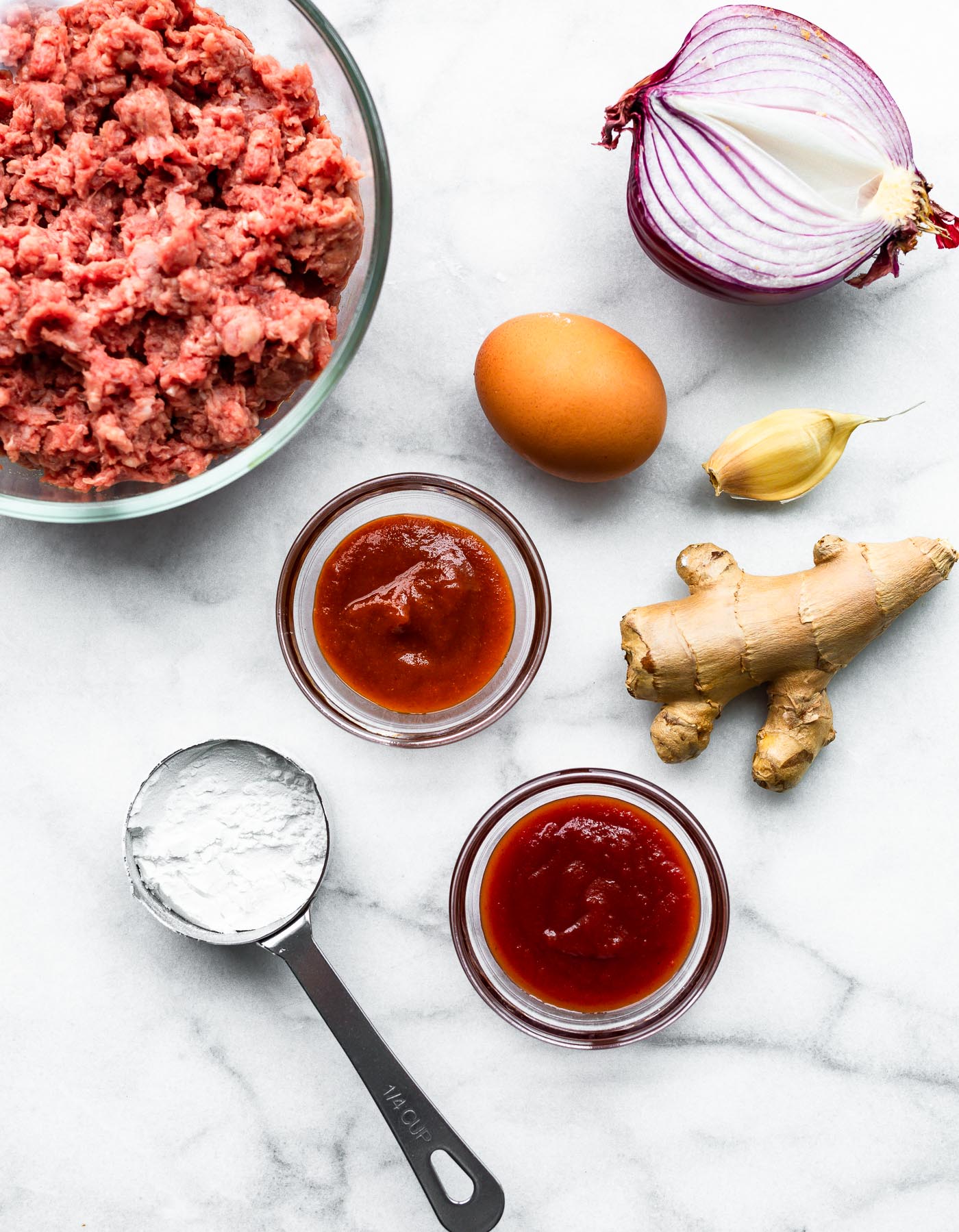 Overhead image of meatballs ingredients on a white tabletop.
