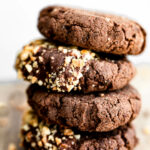 Close up stack of vegan chocolate breakfast cookies with melted chocolate and crushed hazelnuts.