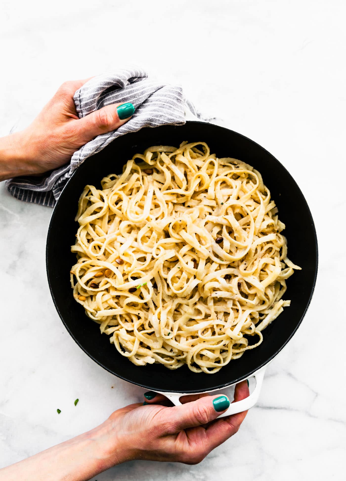 pasta noodles for fettuccine in a pot being held by two hands