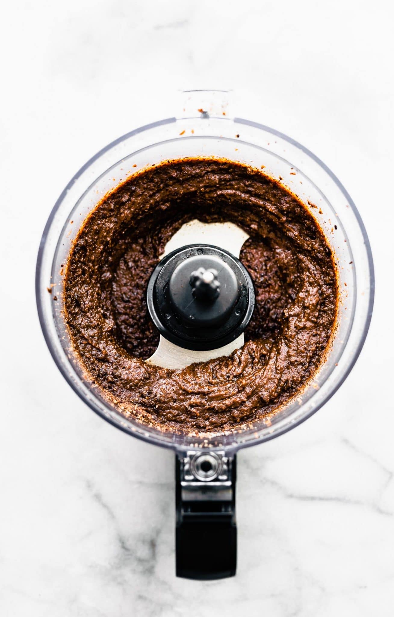 Overhead image of food processor with chocolate cookie batter.