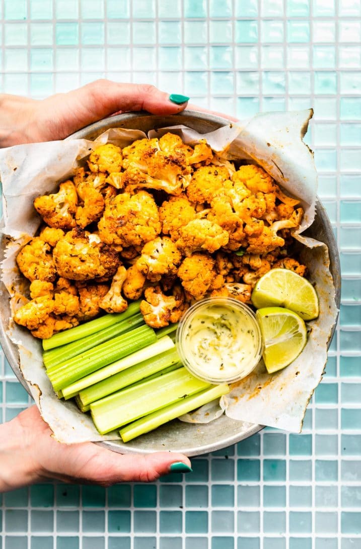 air fryer buffalo cauliflower served with Ranch dipping sauce, celery sticks, and lime wedges