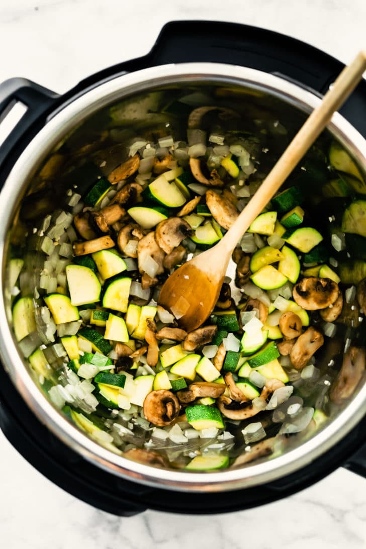 zucchini, onions, and mushrooms, in an instant pot with a wodden spoon