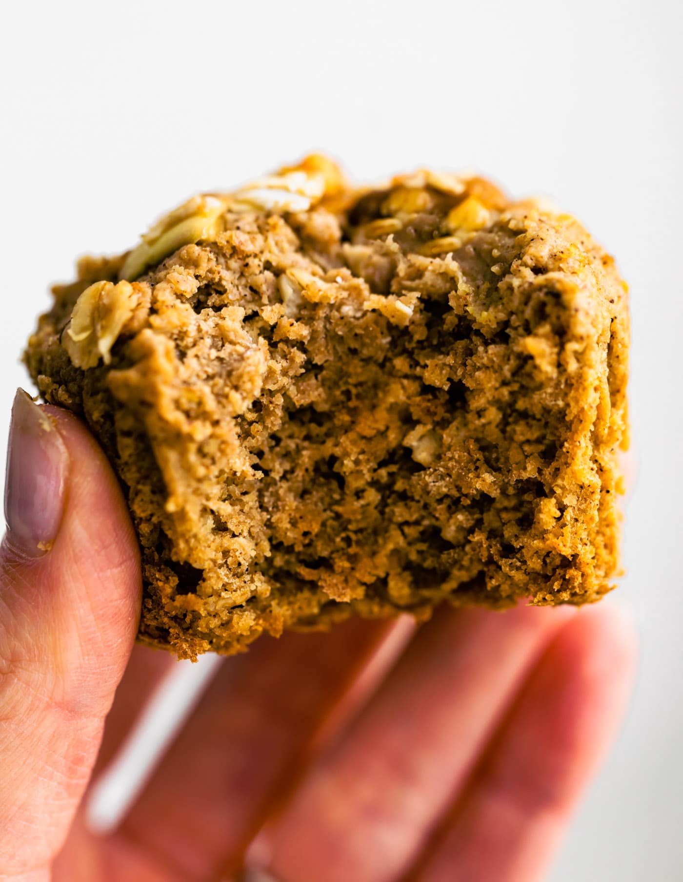 Gluten free apple oatmeal muffin being held with a bite taken out