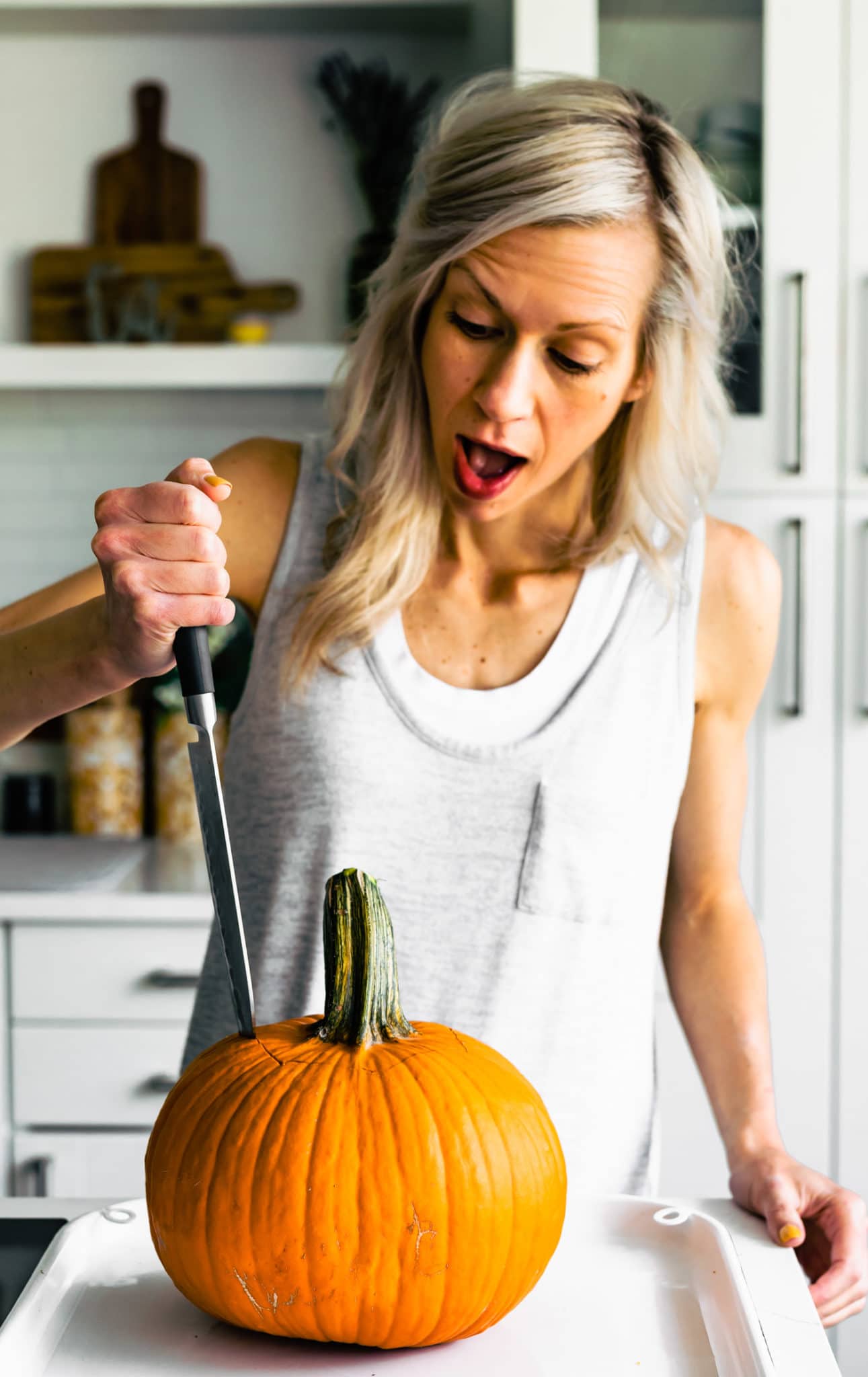 A woman carving a pumpkin with a knife