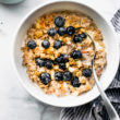 superfood instant pot oatmeal served in a white bowl topped with fresh blueberries and served with a spoon