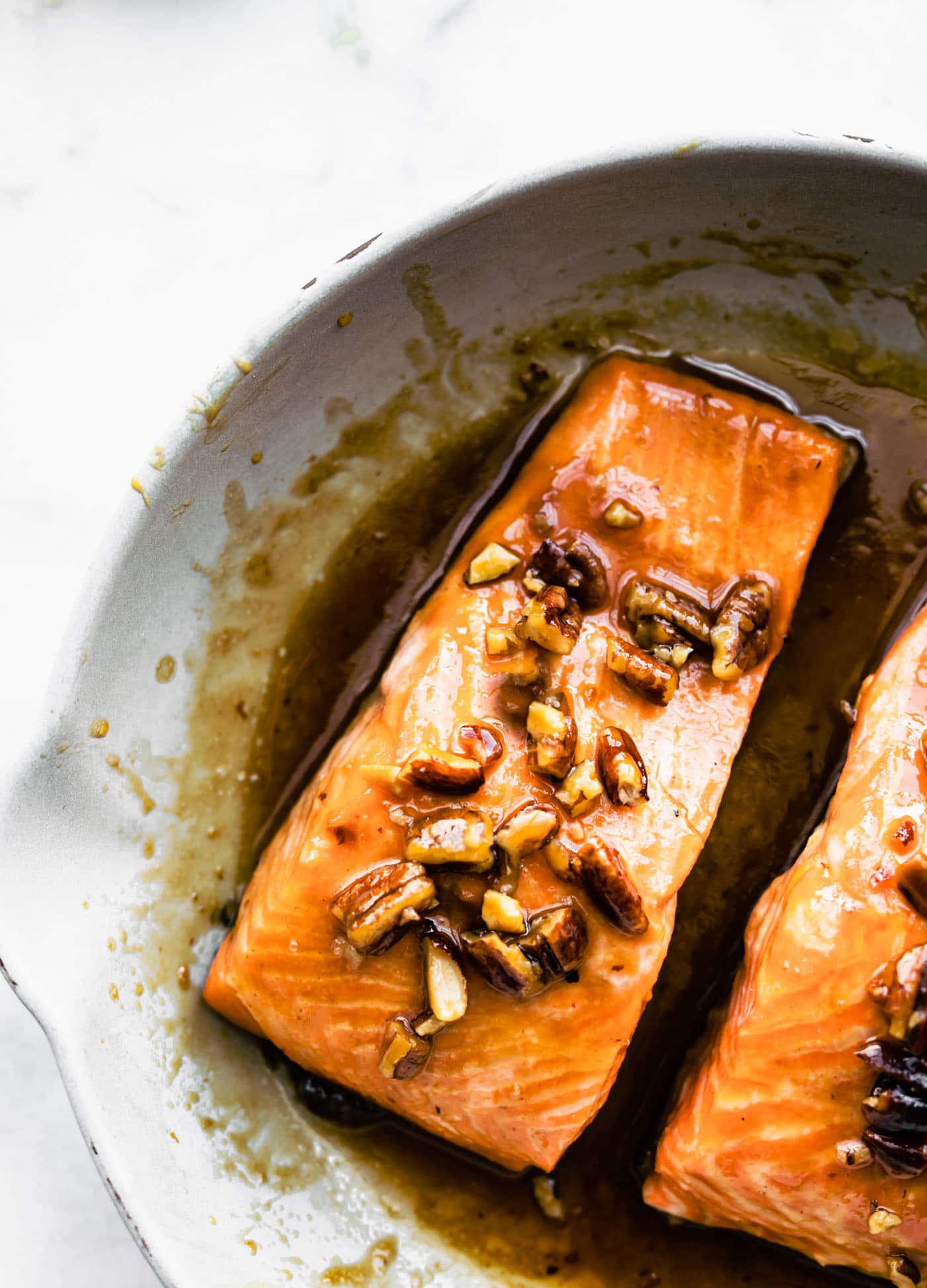 Two salmon filets marinading in a maple bourbon glaze and pecans.