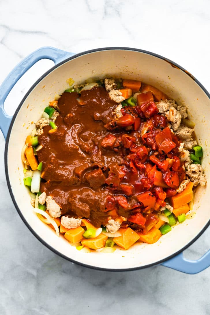sweet potatoes, veggeis, and mole sauce in a pot for turkey chili