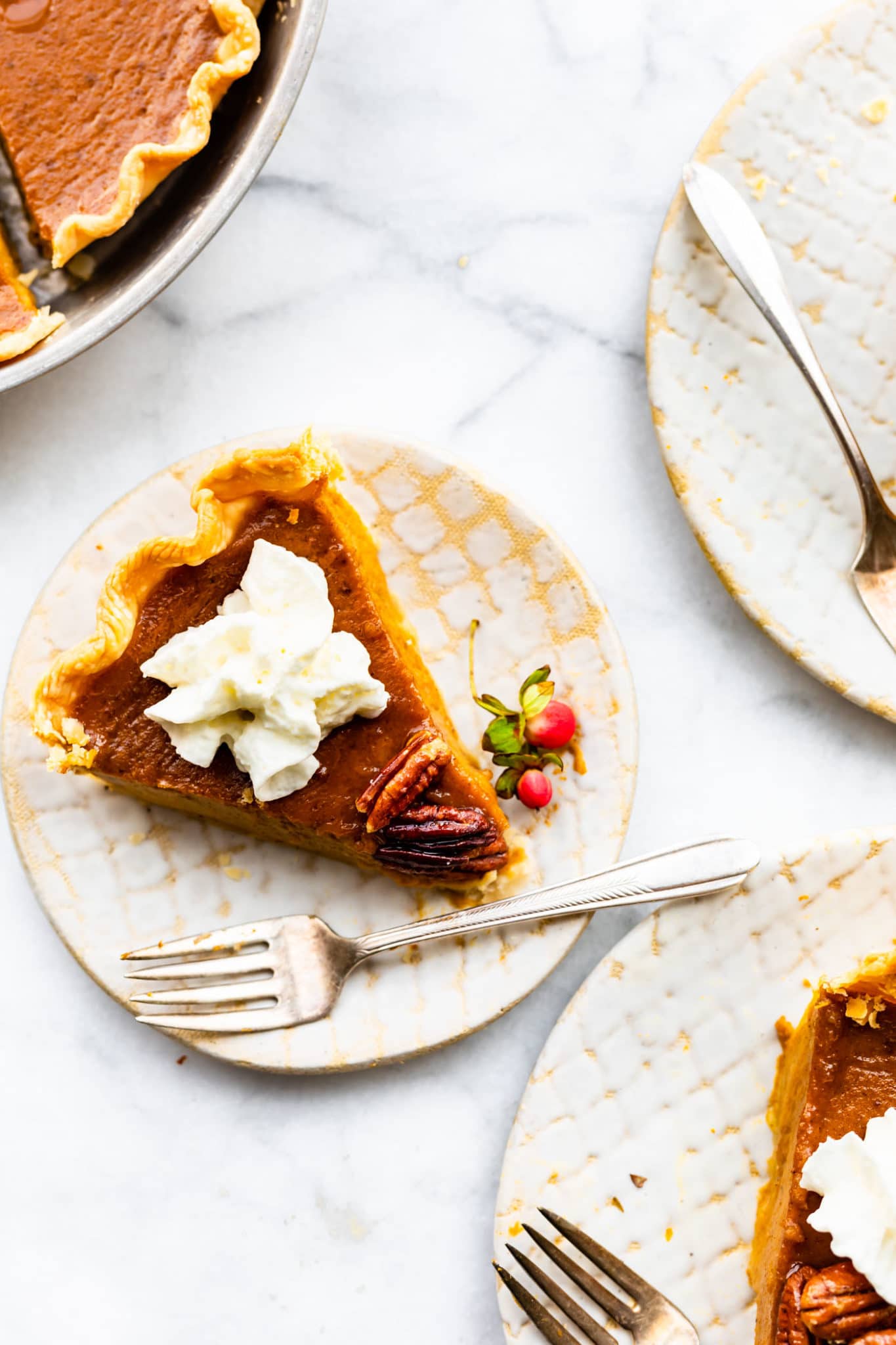 slice of gluten free pumpkin pie on a plate topped with dairy-free whipped cream with a fork on the side