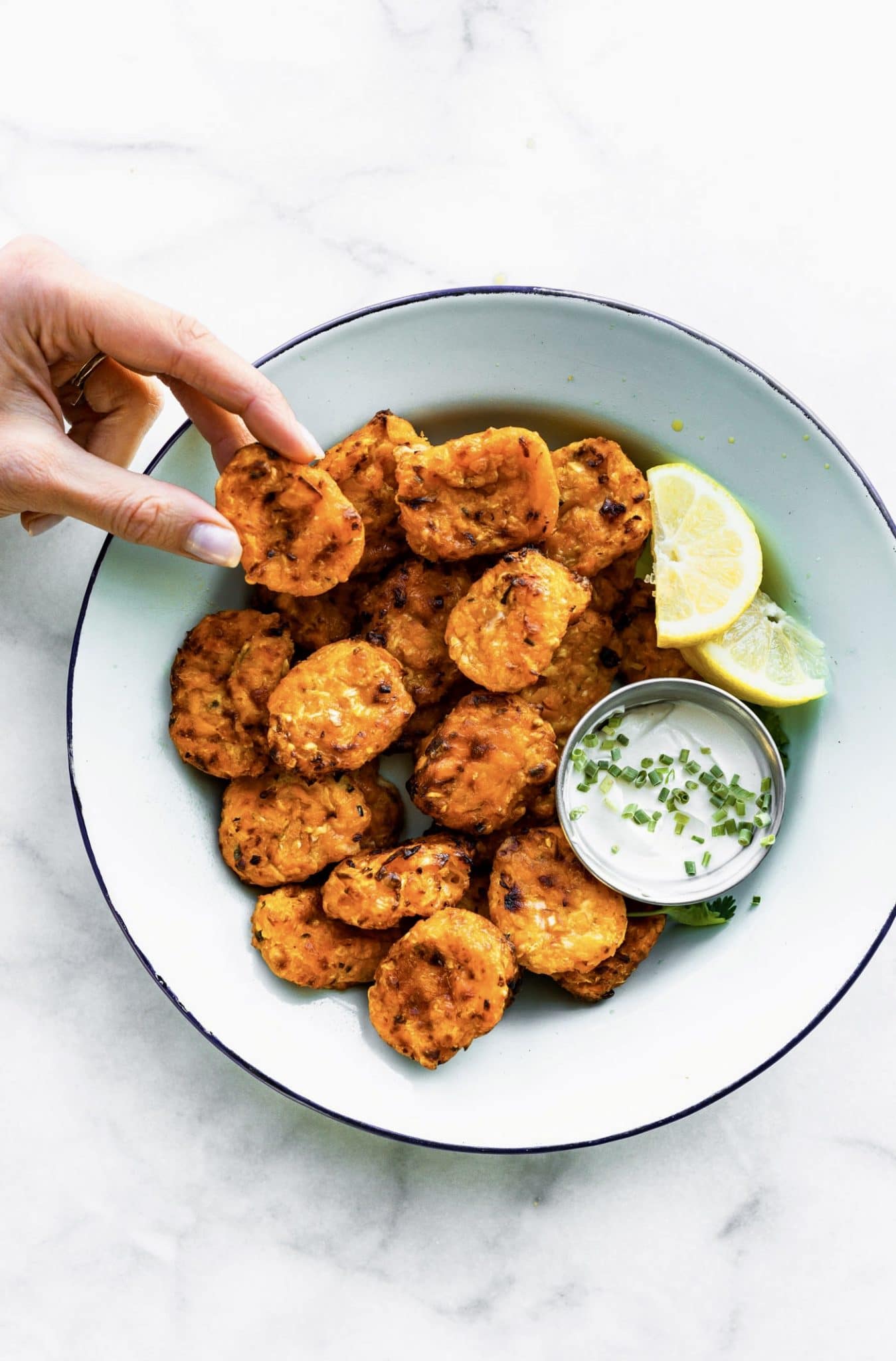 cauliflower sweet potato tots in a bowl with dip and lemon wedges