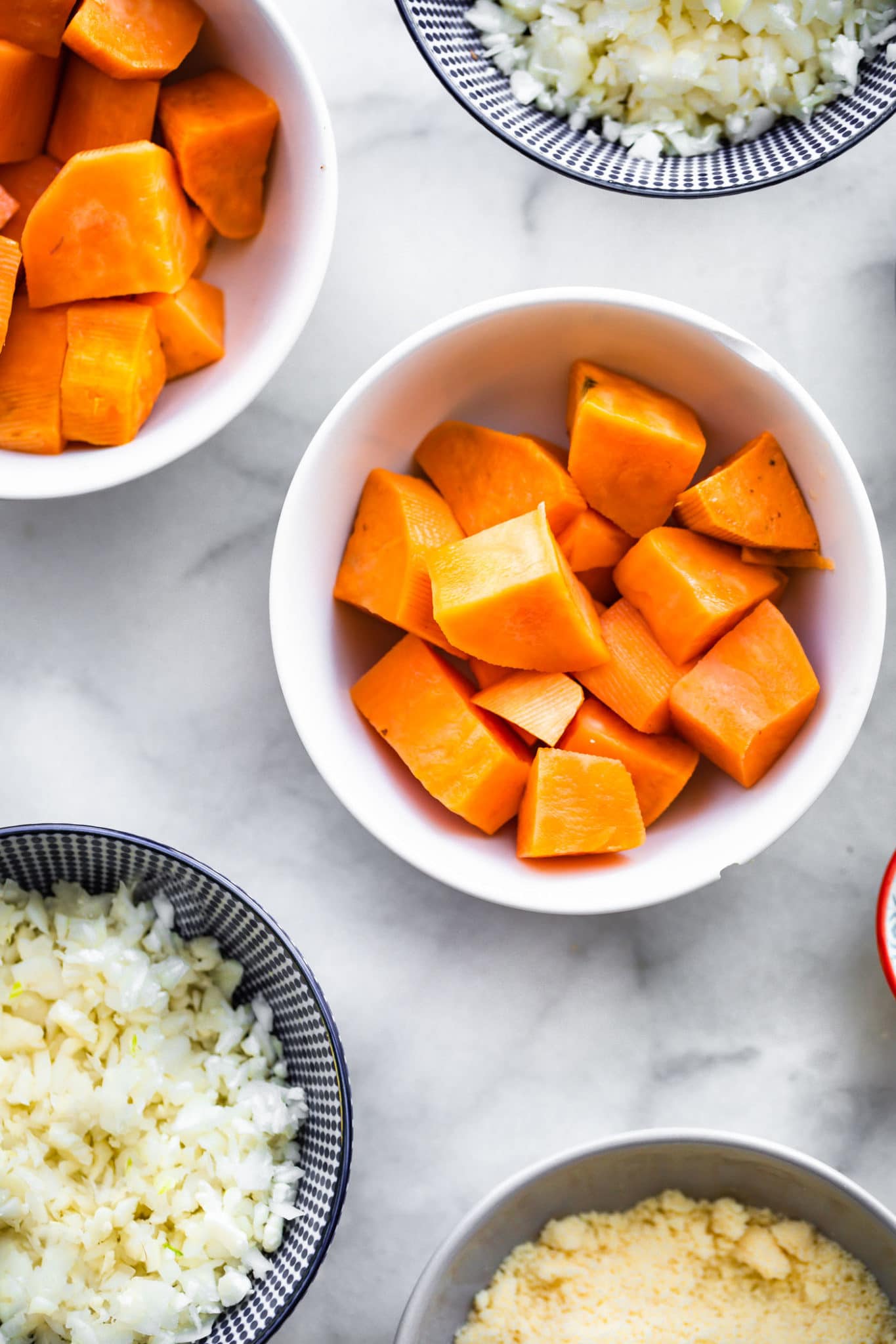 sweet potatoes, reiced cauliflower, and ingredients for sweet potato tots in mixing bowls