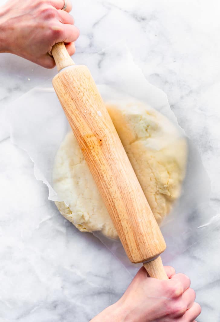 gluten free biscuit dough being rolled out with a rolling pin