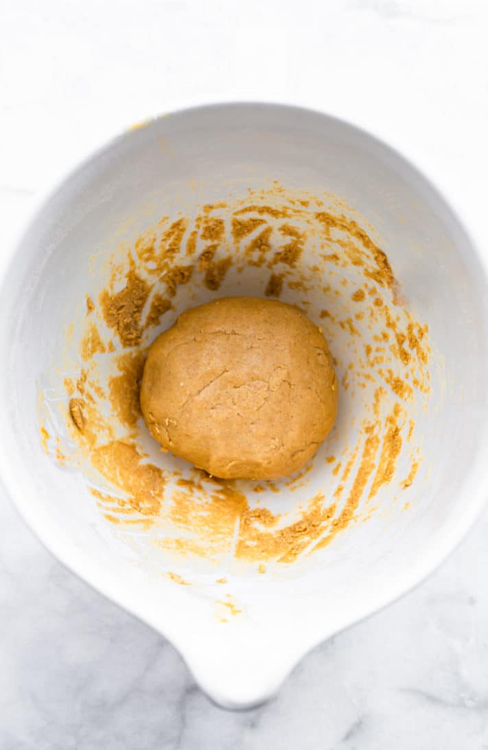 A gluten free cookie dough ball in a white bowl