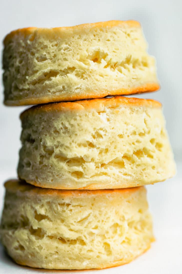Close up side view of three gluten free biscuits stacked on top of each together to show fluffy and flaky texture.