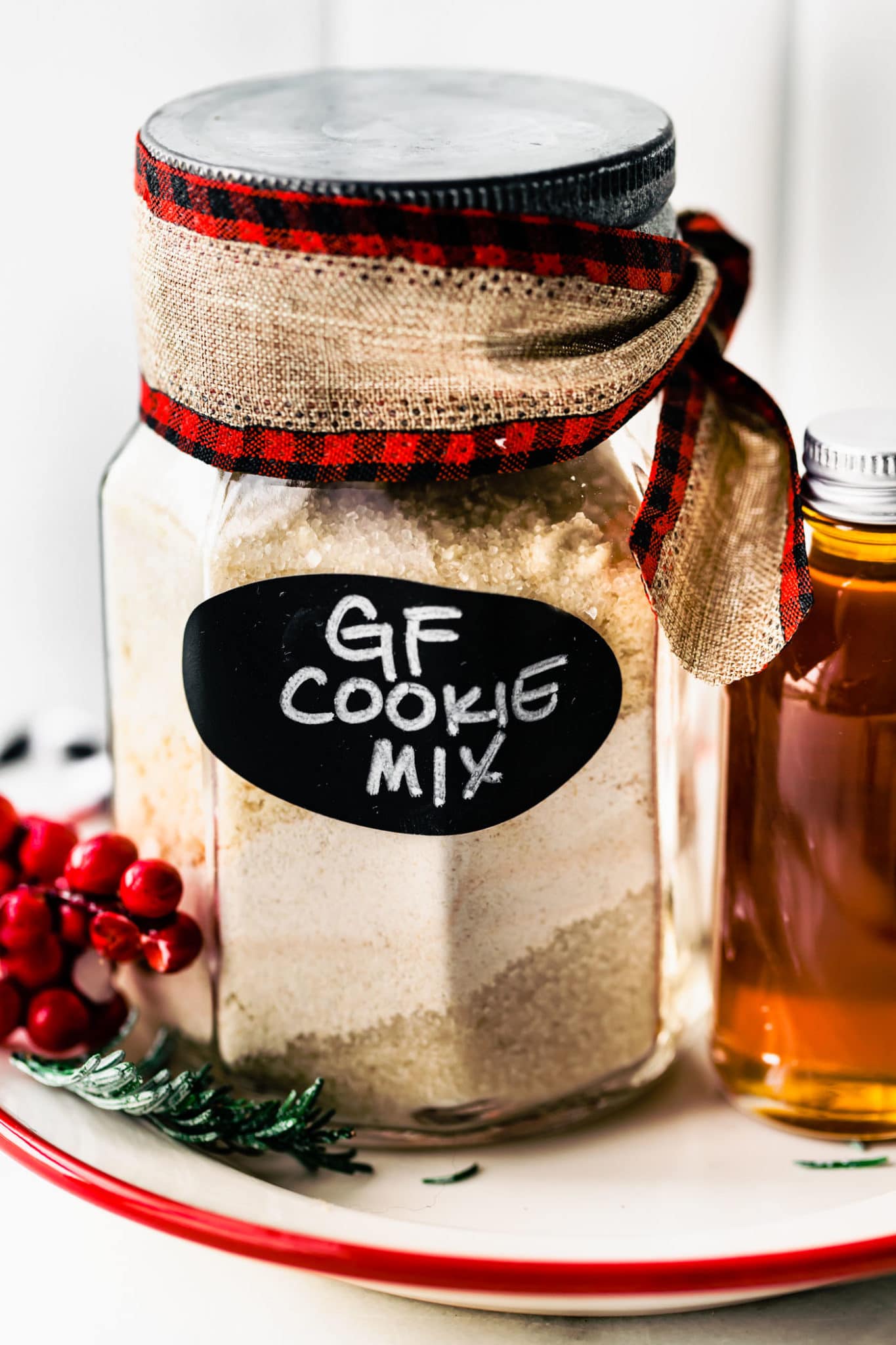 Gluten free cookie mix in a jar with black label with white words for gf cookie mix, a Christmas ribbon tied along the top of jar.