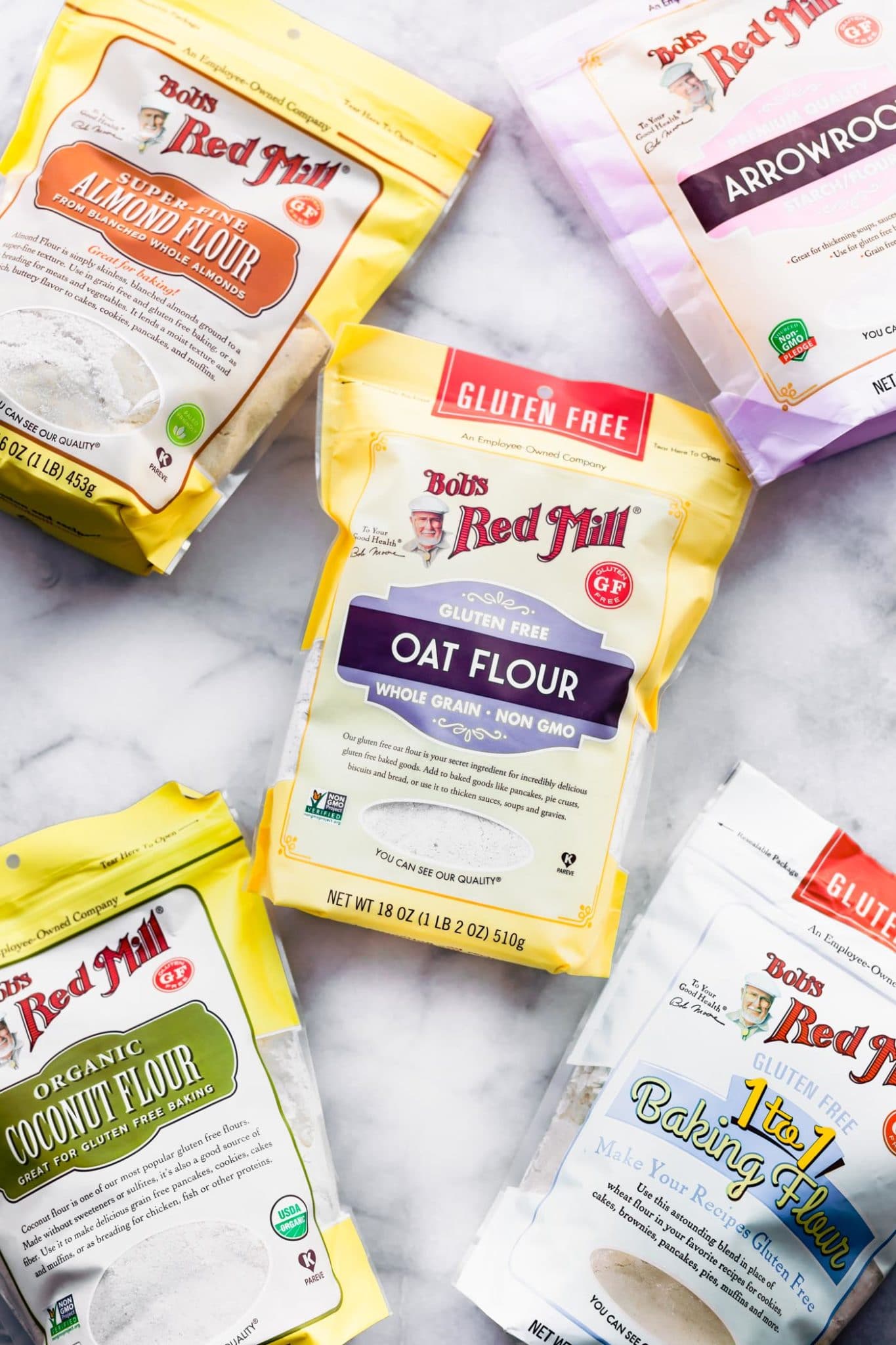 Various Bob's Red Mill Gluten Free Flour Alternatives in packages laying on a marble countertop.