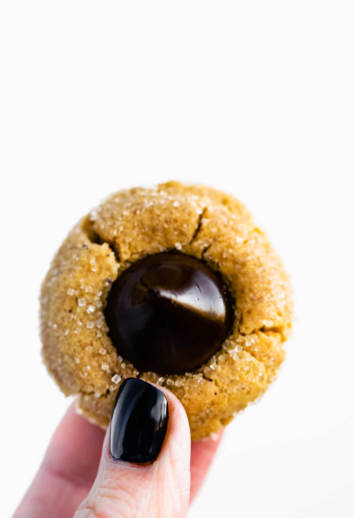 two fingers holding a gluten free peanut butter blossom cookie