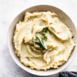 HERO SHOT - A white bowl full of slow cooker dairy free mashed potatoes topped with fresh herbs