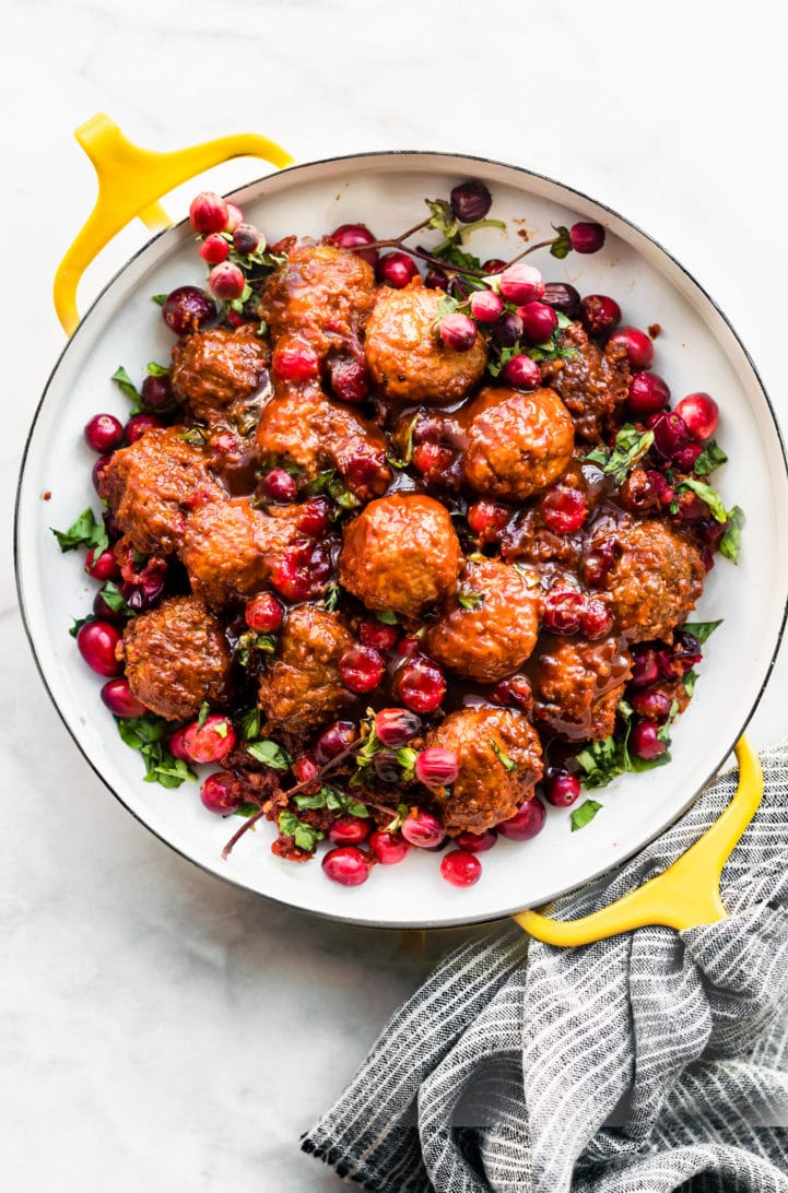 slow cooker gluten free meatballs with cranberry sauce on a serving dish topped with extra cranberries
